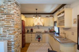 una cocina con armarios blancos y una pared de ladrillo en Alorama Luxury House in Pelion, en Drakeia