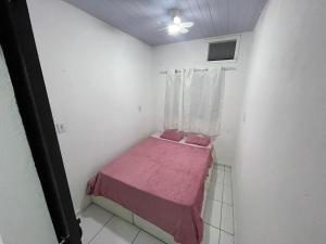 a small bedroom with a pink bed and a window at Cantinho de São Chico in São Francisco do Sul