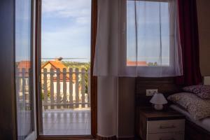 a bedroom with a window with a view of a balcony at Grüne Oase Apartman in Hévíz +3 photos
