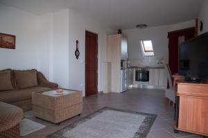 a living room with a couch and a tv at Grüne Oase Apartman in Hévíz