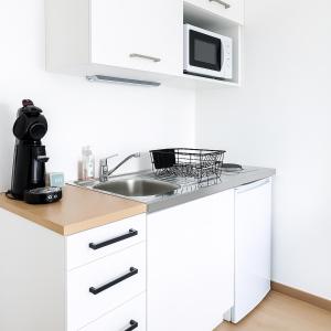 a white kitchen with a sink and a microwave at Le Cocon - Vue panoramique Strasbourg - Wifi - Netflix in Strasbourg