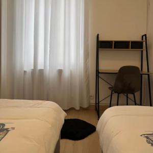 a bedroom with two beds and a chair and a window at Noami in Montigny-lès-Metz