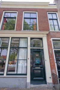 una casa de ladrillo con una puerta verde y ventanas en De Grote Sluis, en Harlingen