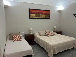 a bedroom with two beds and a picture on the wall at Dammuso Rekhale in Scauri