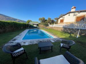 a backyard with a swimming pool with chairs and a table at Encinar del Abuelo in Casas del Castañar