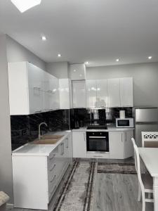 a kitchen with white cabinets and a sink and a table at Eriksens Apartment in Pogradec +7 photos