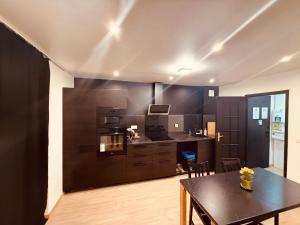 cocina con armarios negros y mesa negra en La Suite Mulhouse, en Mulhouse