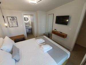 a bedroom with a white bed with towels on it at GeoMar Luxury Apartments in Skala Marion