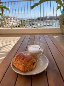 a plate with a cup of milk and a pastry on a table at Duplex sur le Golfe de Saint Tropez - Panoramic View in Cogolin