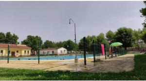 a swimming pool with a green umbrella and a pool at El Rincón del Mirador in Carboneras de Guadazaón