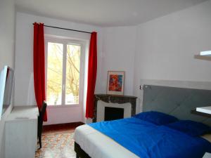 a bedroom with a bed and a window with red curtains at Hôtel le Moderne in Saint-Paul-le-Jeune