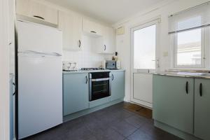 a kitchen with white cabinets and a blue refrigerator at Peaceful Riverside Lodge Free Parking in Christchurch