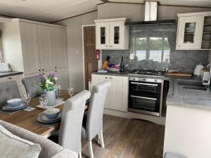 une cuisine avec une table, des chaises et une cuisinière dans l'établissement Tattershall Lakes Jet Ski Lake 3 Bedroom Cabin with Private jet ski dock, à Tattershall