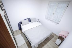 a small white bedroom with a bed and a window at Čemerno Mountain House in Gacko