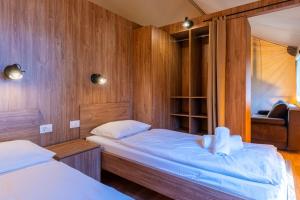 two twin beds in a room with wooden walls at Adria Glamping luxury tents Camping Poljana Mali Lošinj in Mali Lošinj