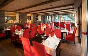 jadalnia z czerwonymi krzesłami i stołami w restauracji w obiekcie Hotel Restaurant Waldhaus w mieście Leukerbad