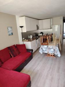 a living room with a red couch and a kitchen at Appart 4-7 pers La Mongie in Bagnères-de-Bigorre