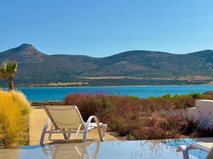 a chair sitting next to a body of water at Farous seaside sunset villa II in Antiparos