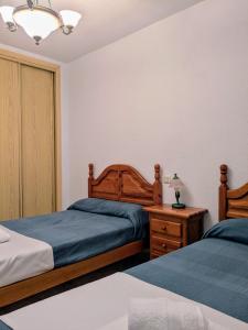 a bedroom with two beds and a night stand with a lamp at Casa Alba in Escalona