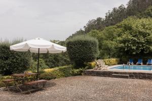 a patio with an umbrella and a swimming pool at Casa da Janeira in Vieira do Minho