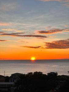 D View Cozy Corner في Gouyave: غروب الشمس على المحيط مع الشمس في السماء +12 صورة
