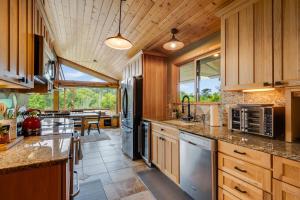 a large kitchen with wooden cabinets and a large window at Four Seasons Cabin, ONP, Olympic Trail, Hot-tub in Port Angeles