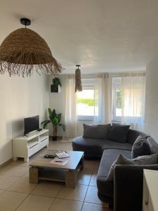a living room with a couch and a table at LE FAMILIAL 6 PERSONNES WIFi PARKING in Bébing