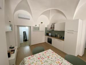 une cuisine avec des armoires blanches et une table et une salle à manger dans l'établissement La Casa sul Corso, à Ascoli Piceno