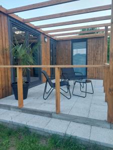 a patio with two chairs and a pergola at Domek letniskowy Osieki Parkowa in Osieki