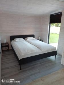 a large bed in a bedroom with a large window at Domek letniskowy Osieki Parkowa in Osieki