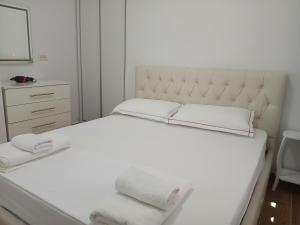 een wit bed met twee witte handdoeken erop bij Amantius Apartments Borsh Himare in Borsh