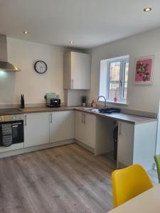 eine Küche mit weißen Schränken und einer Uhr an der Wand in der Unterkunft Bright & Spacious 3-Bed Rotherham Home Ideal for Families or Contractors in Kimberworth