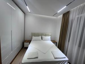 ドゥラスにあるGimi Premium Apartmentsの白いシーツが敷かれた大きなベッドのある寝室