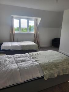 zwei Betten in einem Schlafzimmer mit Fenster in der Unterkunft Bright & Spacious 3-Bed Rotherham Home Ideal for Families or Contractors in Kimberworth
