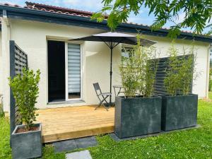 a house with a wooden deck with an umbrella at 2 Pieces - Cosy - Parking Securisé in Gradignan
