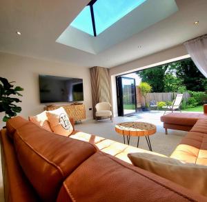 a living room with a brown leather couch and a tv at Modern Luxury Home with Spacious Garden close to Warner Bros Studio in Abbots Langley