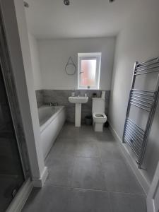 a bathroom with a tub and a toilet and a sink at Modern 3-Bed House in Rotherham, WiFi, Garden & Free Parking in Kimberworth +16 photos