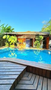 a large swimming pool with a wooden deck next to a house at Casa Jardim Bangalos in Paraty