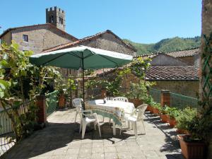 einen Tisch und Stühle mit Sonnenschirm auf einer Terrasse in der Unterkunft Casa Ginevra in Bagni di Lucca