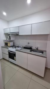 Una cocina blanca con estufa y fregadero. en Departamento Bahia Blanca, en Bahía Blanca 6 fotos más