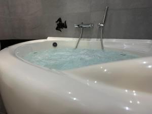 a bath tub filled with blue water in a bathroom at Paceville Sandy Beach with Jacuzzi & Free Parking in St Julian's