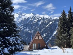 una piccola cabina nella neve con montagne sullo sfondo di Fantastic view - Chalet Karakol a Karakol