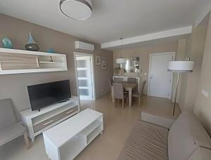 un salon avec une télévision et une table dans l'établissement Costa Azahar - En Primera Línea, à El Borseral