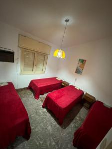 two beds in a room with red sheets at Casa BUENOS AIRES in Villa María