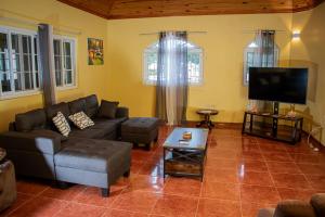 ein Wohnzimmer mit Sofa und Flachbildfernseher in der Unterkunft KoolVille in Mandeville