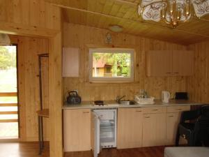a kitchen with a stove and a sink and a window at Domki Nad Jeziorem Karłowice in Karłowice