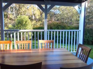 a wooden table and four chairs on a porch at 2 bedrooms private bathroom 2 queen beds own entry in Long Jetty