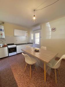 a kitchen with a wooden table and white chairs at N&G Alquiler Temporal in Venado Tuerto