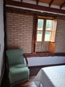 een slaapkamer met een groene stoel en een raam bij Chalé Cores da Mata Inaugurado recente - novinho in Carrancas