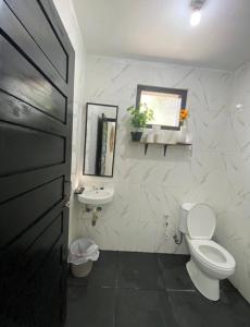 a white bathroom with a toilet and a sink at Stunning Family Friendly House Nearby Lampuuk Beach in Banda Aceh +10 photos